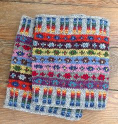 two multicolored knitted napkins sitting on top of a wooden table