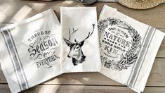 three tea towels with designs on them sitting on a wooden table next to a straw hat