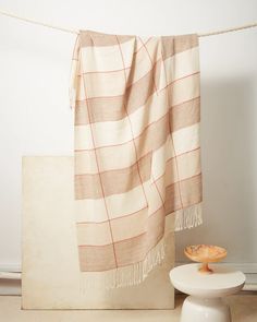 a towel hanging on a clothes line next to a white chair and table with an orange bowl