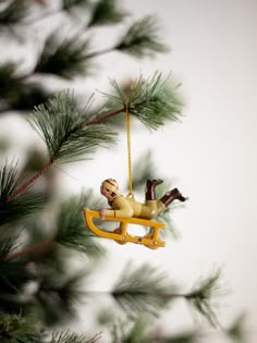 a christmas ornament hanging from a pine tree with a man on a sleigh