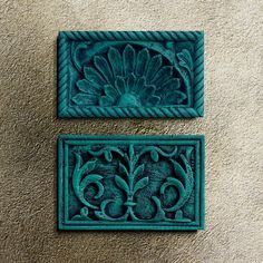 two decorative tile pieces on the wall, one with a flower and leaves in it