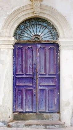 an old purple door with arched glass above it