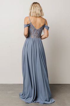 the back of a woman wearing a long blue dress with lace detailing on it and open shoulders