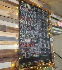 a restaurant menu board with lights on the wall and wooden planks behind it,