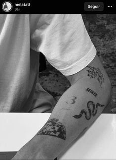 a person with a tattoo on their arm sitting at a table in front of a cell phone