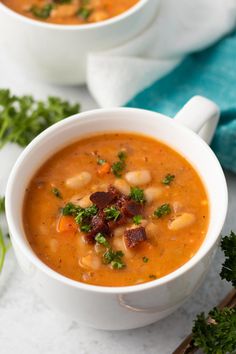 two white bowls filled with soup and garnished with parsley on the side