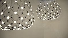 two lights hanging from the ceiling with white and black dots on them, one light is turned on