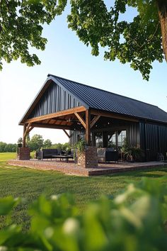 a large black metal building sitting on top of a lush green field next to a tree