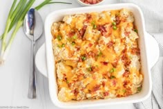 a casserole dish with meat, cheese and vegetables in it next to a spoon