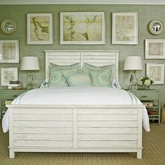 a bedroom with green walls and pictures on the wall above the bed, along with two lamps