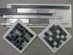 two pieces of silver and black glass tile sitting next to each other on a table