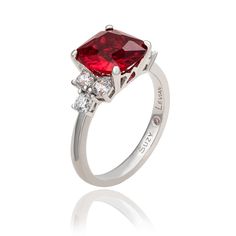 From the day he bends down on one knee through your 50th wedding anniversary and beyond, the sparkle in this gemstone ring will rival the sparkle in his eyes when he looks at you. Made of 925 sterling silver, this fabulous ring features a cushion cut red cubic zirconia center stone, sided by three white cubic zirconia's prong set on each side. If you are in the market for an affordable engagement ring that blends traditional with a dash of originality then this one is perfect for you. Every sing Classic Red Sapphire Promise Ring, Luxury Red Sapphire Wedding Ring, Luxury Red Birthstone Ring For Anniversary, Timeless Diamond Ruby Ring For Anniversary, Red Emerald Cut Diamond Ring For Anniversary, Fine Jewelry Ruby Ring With Center Stone For Anniversary, Timeless Diamond Ruby Anniversary Ring, Emerald Cut Red Ring For Anniversary, Diamond Ruby Ring With Accent Stones For Anniversary