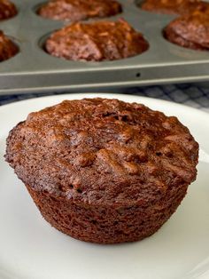 a chocolate muffin on a plate next to a muffin pan