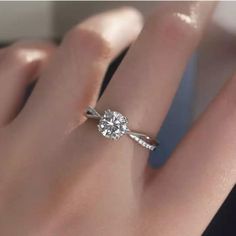 a woman's hand with a diamond ring on her left hand and the other hand holding an engagement ring