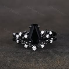 a black diamond ring with white diamonds on the sides and an intricate design around it