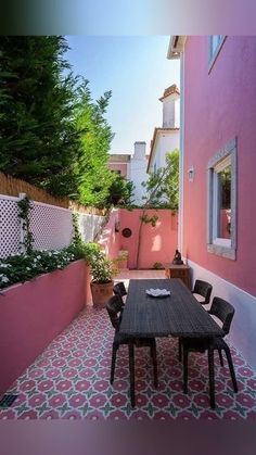 an outdoor dining area with pink walls and tiled floor