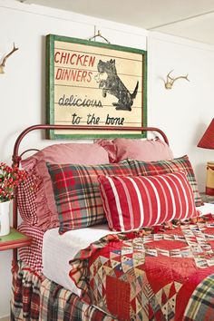 a bed with red and white quilts on it, next to a table lamp