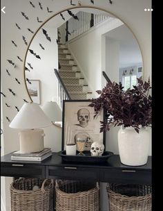 an entryway with baskets and a mirror on the side table next to a staircase