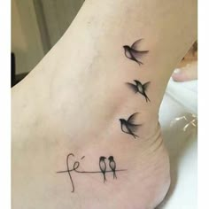 a small tattoo on the foot of a woman with birds flying above her head and two letters