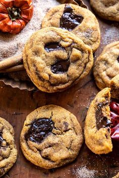 chocolate chip cookies are arranged on a wooden board with powdered sugar and dried cherries