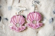 Catch the wave with these bright pink Clam and Pearl acrylic earrings! Perfect for those who can't get enough of the beach or who love to stand out with unique, eye-catching jewelry these sparkly earrings add a splash of ocean fun to any outfit. Whether you're beach-bound or just daydreaming of the sea, these funky earrings are sure to turn heads. Dive into your summer style with these eye-catching accessories! 🌊🐚 -Earrings measure about 2.5in tall with hook included, and about 1.4in wide *Jewelry hardware crafted from tarnish resistant and sturdy hypoallergenic surgical stainless steel. *Keep out of direct sun exposure for prolonged periods. *Refrain from exposing to water, fragrances, or harsh chemicals. *For cleaning, use a soft cloth with gentle strokes, avoiding painted sections. Unique Nickel-free Pink Earrings, Unique Nickel Free Pink Earrings, Pink Dangle Earrings For Beach, Pink Beach Jewelry With Matching Earrings, Pink Jewelry With Matching Earrings For Beach, Unique Pink Pierced Earrings, Pink Dangle Plug Earrings, Pink Dangle Plug Earrings For Pierced Ears, Unique Pink Hoop Earrings As Gift