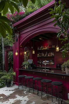 an outdoor bar with stools and potted plants on the outside, surrounded by greenery