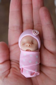 a tiny baby doll is held in someone's hand