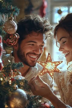 a man and woman holding a star in front of a christmas tree with ornaments on it