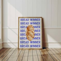 a poster with bread on it sitting in a room next to a wooden floor and white walls