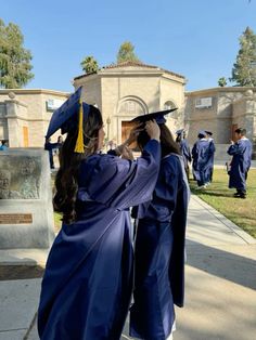 two graduates in blue gowns and caps stand at the end of their graduation ceremony