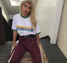 a woman sitting on top of a wooden bench wearing purple pants and a white t - shirt