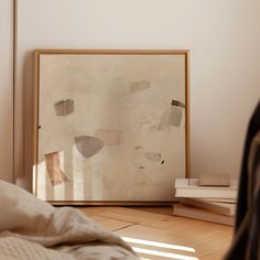 a painting sitting on top of a wooden floor next to a white bed and pillows