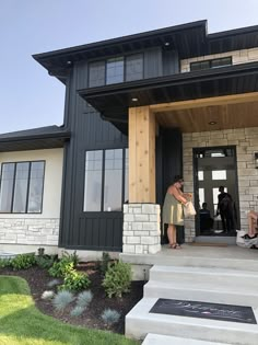 two people are standing on the front steps of a house