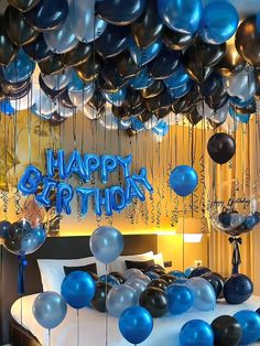 balloons and streamers are floating in the air above a bed with a birthday sign on it