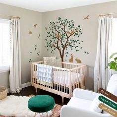 a baby's room decorated in white and green with a tree painted on the wall