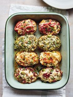 baked stuffed tomatoes in a casserole dish with cheese and herbs on the top