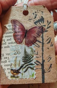 a hand holding a small tag with a butterfly on it's side and words written in the middle