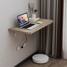 a laptop computer sitting on top of a wooden desk next to a wall mounted speaker