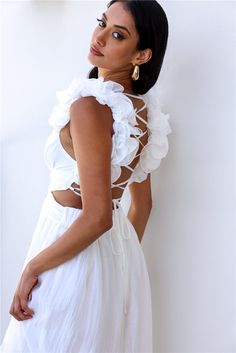 a woman in a white dress posing for the camera with her hands on her hips