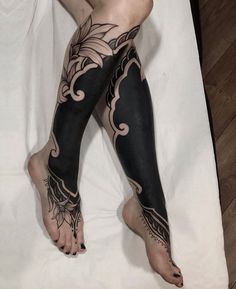 a woman's legs with tattoos on them laying on top of a white sheet