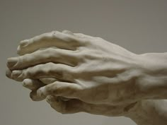 a white statue with two hands on it's back and one hand holding the other