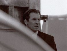 a black and white photo of a man in a suit looking off into the distance