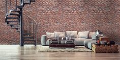 a living room filled with furniture next to a spiral stair case in front of a brick wall