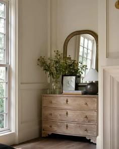 a dresser and mirror in a room with white walls