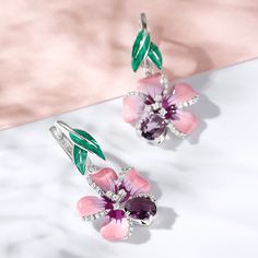 Creating a refreshing appeal with its delicate floral design, this pair of enamel earrings is a masterpiece in itself. These lovely earrings embody the youth of flowers and the freshness of spring. Pink and purple flowers and green enamel leaves are adorned with purple oval-cut stones and white round-cut stones in polished sterling silver. Pair it up with a pretty floral print dress and you're good to go for a happening day out or at a party.Carat Weight: 0.63 ctStone Shape: RoundStone Size: 1,1 Seed Bead Flowers, Bead Flowers, Jewelry Illustration, Pink And Purple Flowers, Sterling Silver Drop Earrings, Enamel Earrings, Green Enamel, Spring Flower, Lovely Earrings