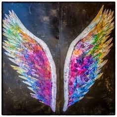 two wings painted on the side of a brick wall with paint splattered all over them