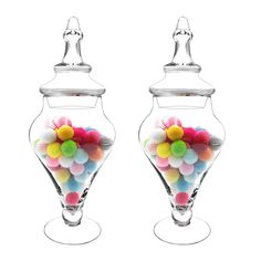 two clear glass vases filled with colorful candies on top of each other in front of a white background