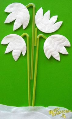 three white paper flowers are on a green background, with the stems in the shape of leaves