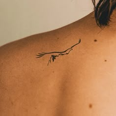 the back of a woman's shoulder with a bird tattoo on her left side