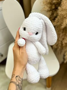 a hand holding a white crocheted stuffed animal in it's left arm